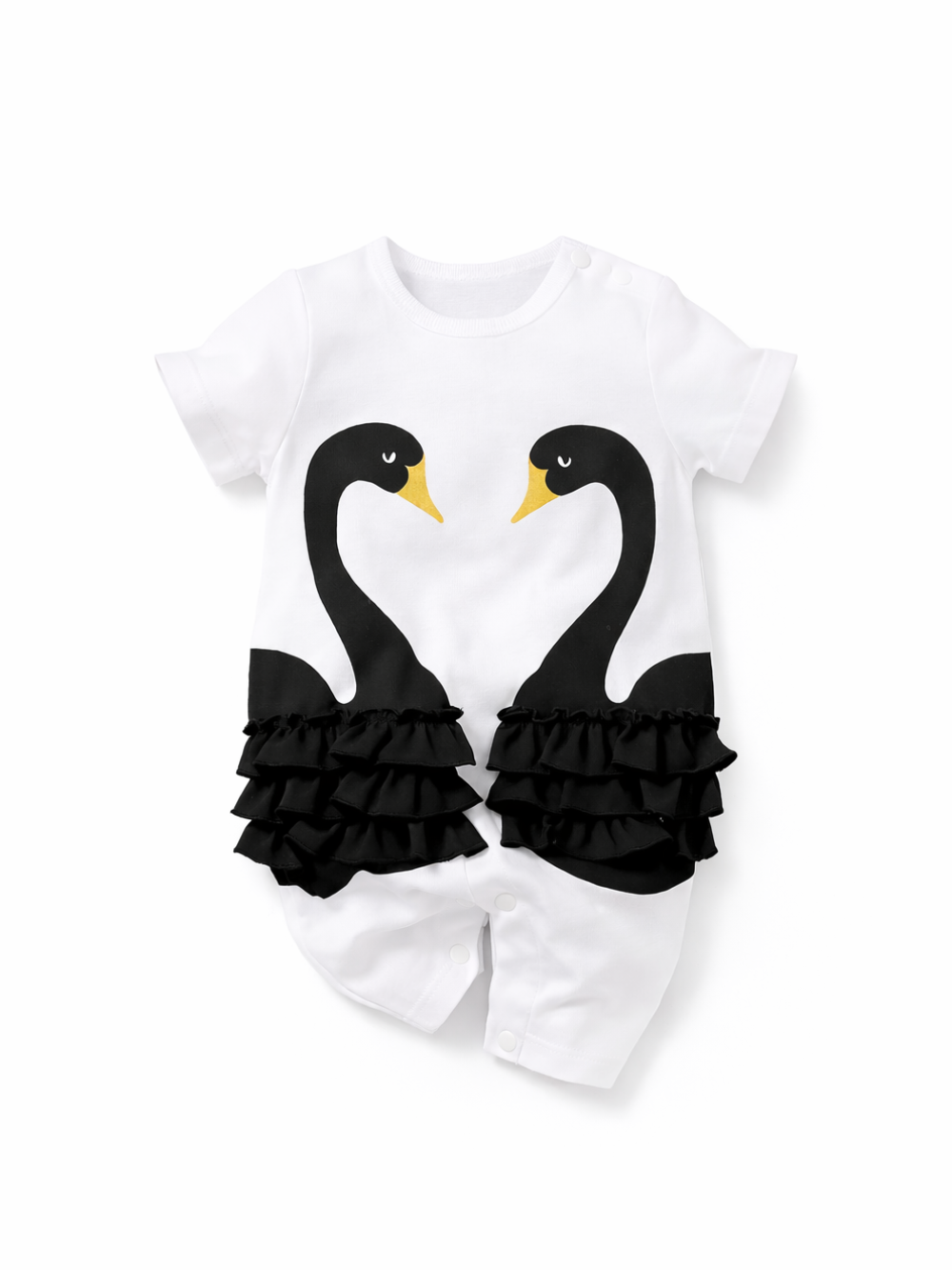 白背景のスタジオ撮影。白い半袖ベビーロンパース単体が中央に配置され、前面に黒い2羽の白鳥プリント（首がハート形）と黄色いくちばしが描かれている。腰まわりには黒いフリルが左右対称に付いており、股下はスナップボタン留め。
