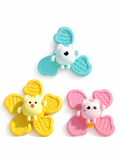 白背景のスタジオ撮影。花びら形のフィジェットトイ3個が三角形に配置されている。上はミントブルー、左下はイエロー、右下はピンクで、中央にクマ風キャラクターのパーツが付いたデザイン。各花びらには波線・格子・凹凸ドットなどの異なるテクスチャーがあり、立体感を出すための柔らかな影が入っている。

