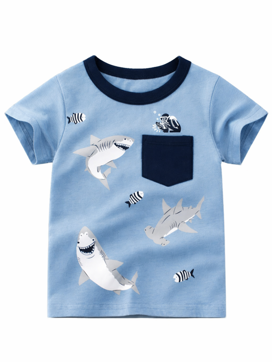 キッズ用ライトブルーTシャツ。ネイビーのリブ襟と胸ポケット付きで、サメとしま模様の小魚、ポケット付近にダイバーのプリントがある。白背景で単品。
