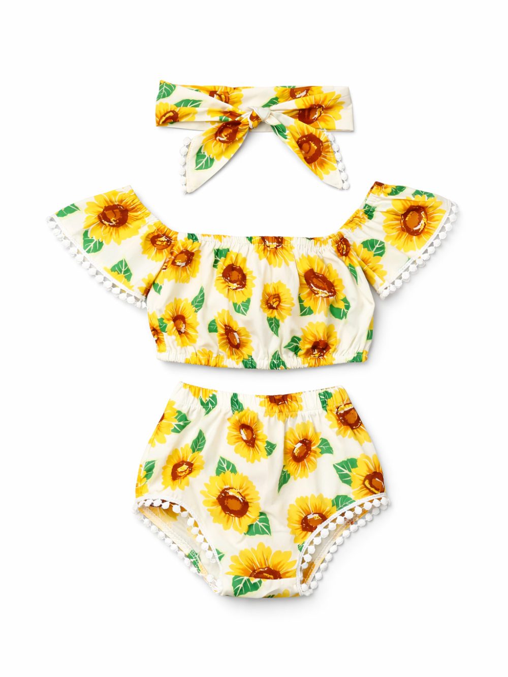 ひまわり柄のキッズ2点セット（トップス＋ショーツ）とリボンヘアバンド。クリーム地に黄色のひまわりとグリーンの葉のプリントで、袖口と裾に白いポンポンレース付き。白背景で単品。
