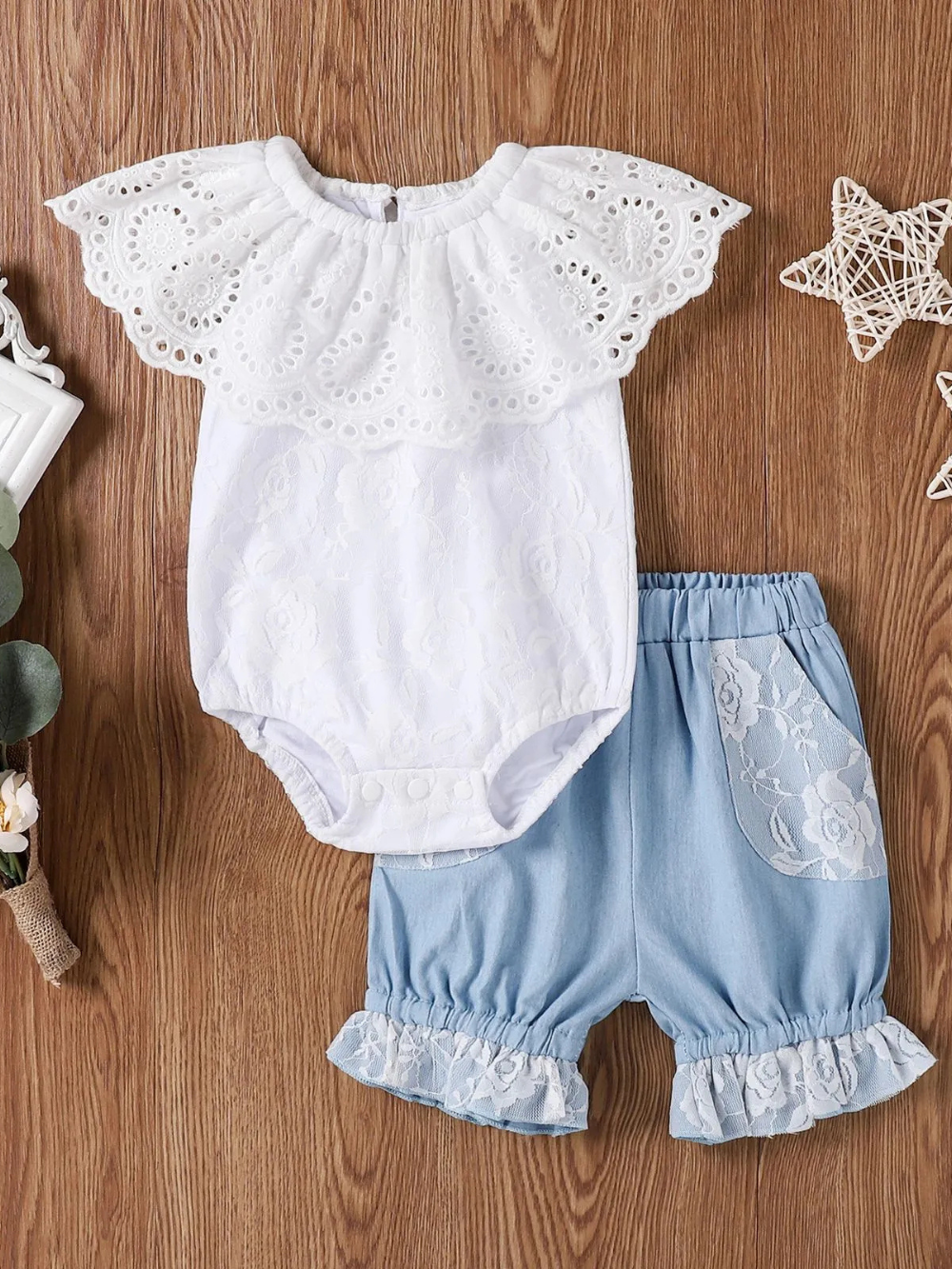 赤ちゃん用2点セット：白いレース襟付きロンパースと、レース装飾のポケット＆裾フリルが付いたライトブルーのブルマ。白背景で商品単体撮影。
