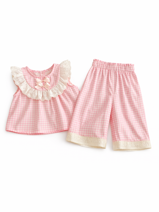 白背景に、ピンクのギンガムチェック柄ノースリーブトップス（レースフリル襟＆リボン付き）と、裾レース付きの同柄クロップドパンツを並べたキッズ2点セット商品画像。
