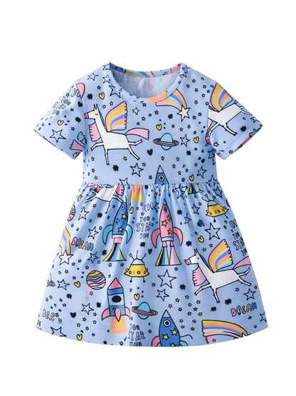 女の子用の半袖ワンピース。淡いブルー地に、ユニコーンやロケット、星や惑星などのカラフルな宇宙柄プリント。白背景で正面からの単品撮影。
