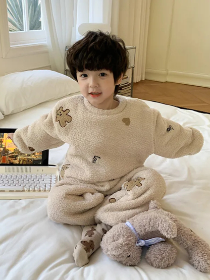 ベージュのふわもこアニマル柄パジャマ上下を着た子どもがベッド横の床に座っている様子
