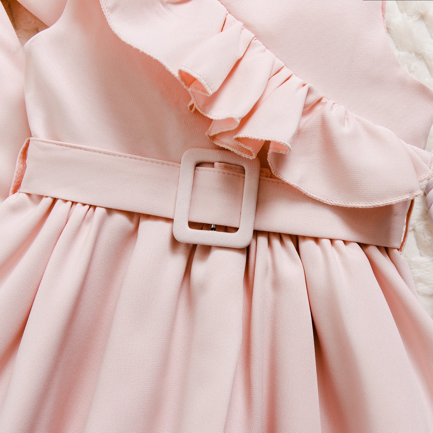 ピンクのフリルワンピースのウエストベルトとギャザー入りスカート部分を近くから撮影したディテール写真
