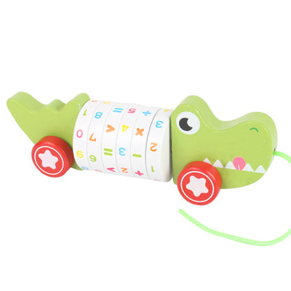 数字と記号が描かれた胴体を持つ緑色の木製ワニ型プルトイが横向きに写っている画像
