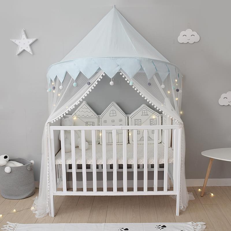 グレーの壁を背景に、白いベビーベッドの上に水色の天蓋蚊帳キャノピーをかけた子ども部屋インテリア（ベビールーム コットン天蓋）
