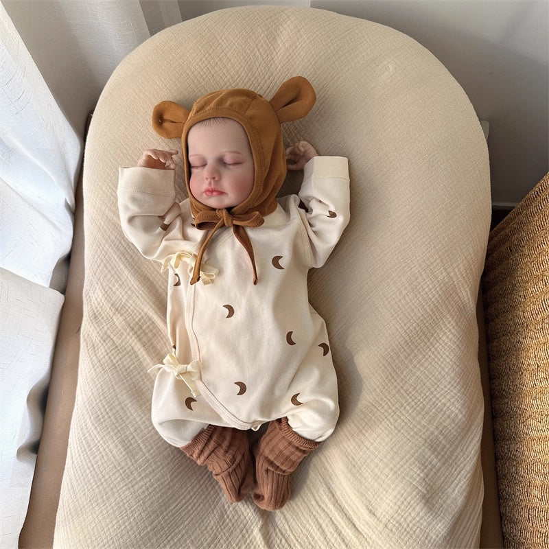 ムーン柄ベビーカバーオールとカラメル耳付き帽子のセットをフラットレイで撮影した画像
