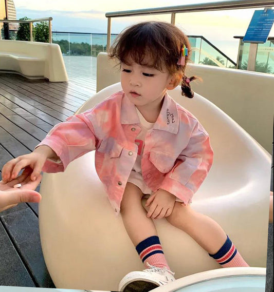 タイダイカラーのガールズデニムジャケットを着てソファに座る女の子の写真
