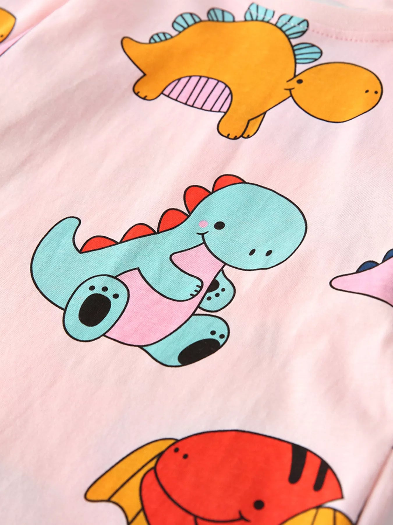 恐竜プリントが全体に描かれたピンクの長袖パジャマトップス
