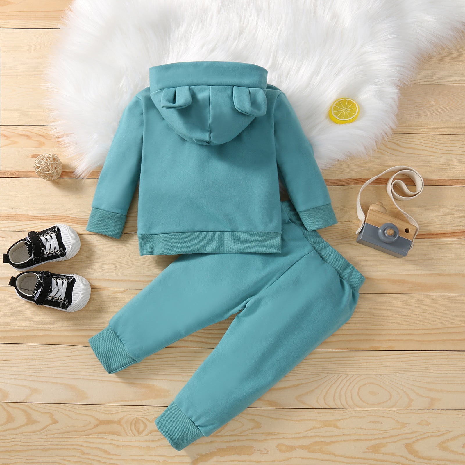 グリーンのフード付き長袖トップスとロングパンツの子どもニットセットアップをシューズ小物と一緒に並べた画像
