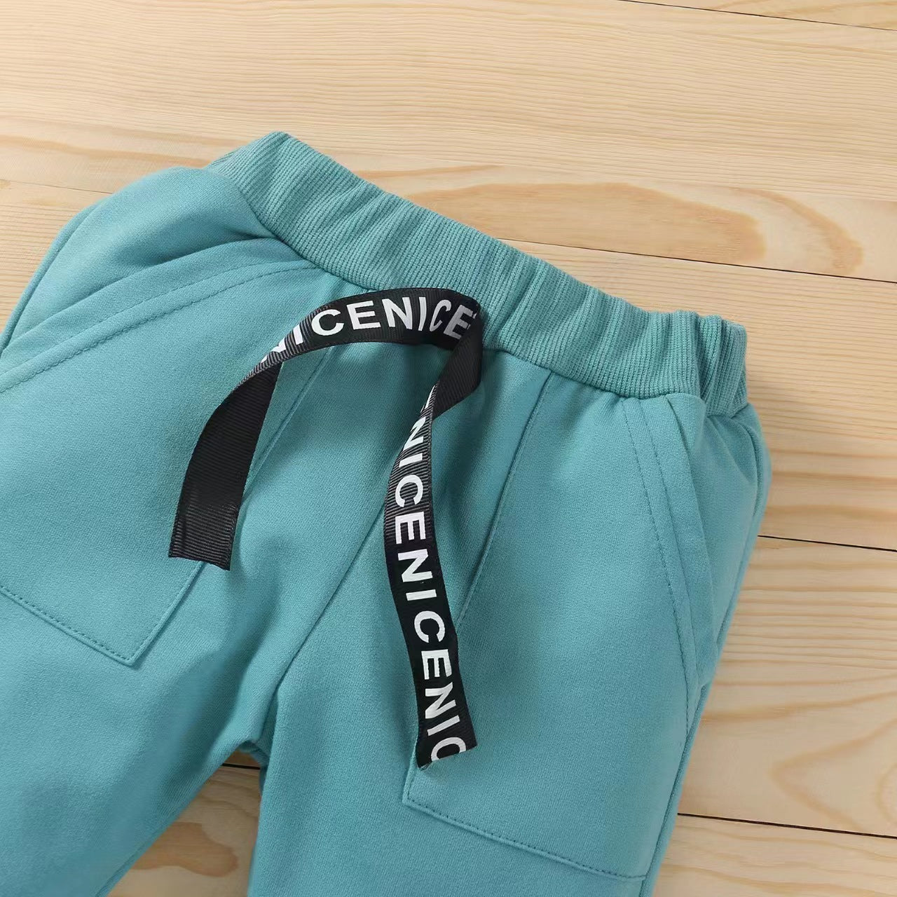 総ゴム仕様のウエストとロゴ入りテープが見えるグリーンロングパンツのウエストディテール
