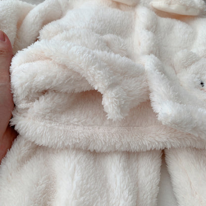 ふわふわしたホワイトボア生地の端を指でつまんだ子ども用くま刺繍ボア上下セットの質感クローズアップ
