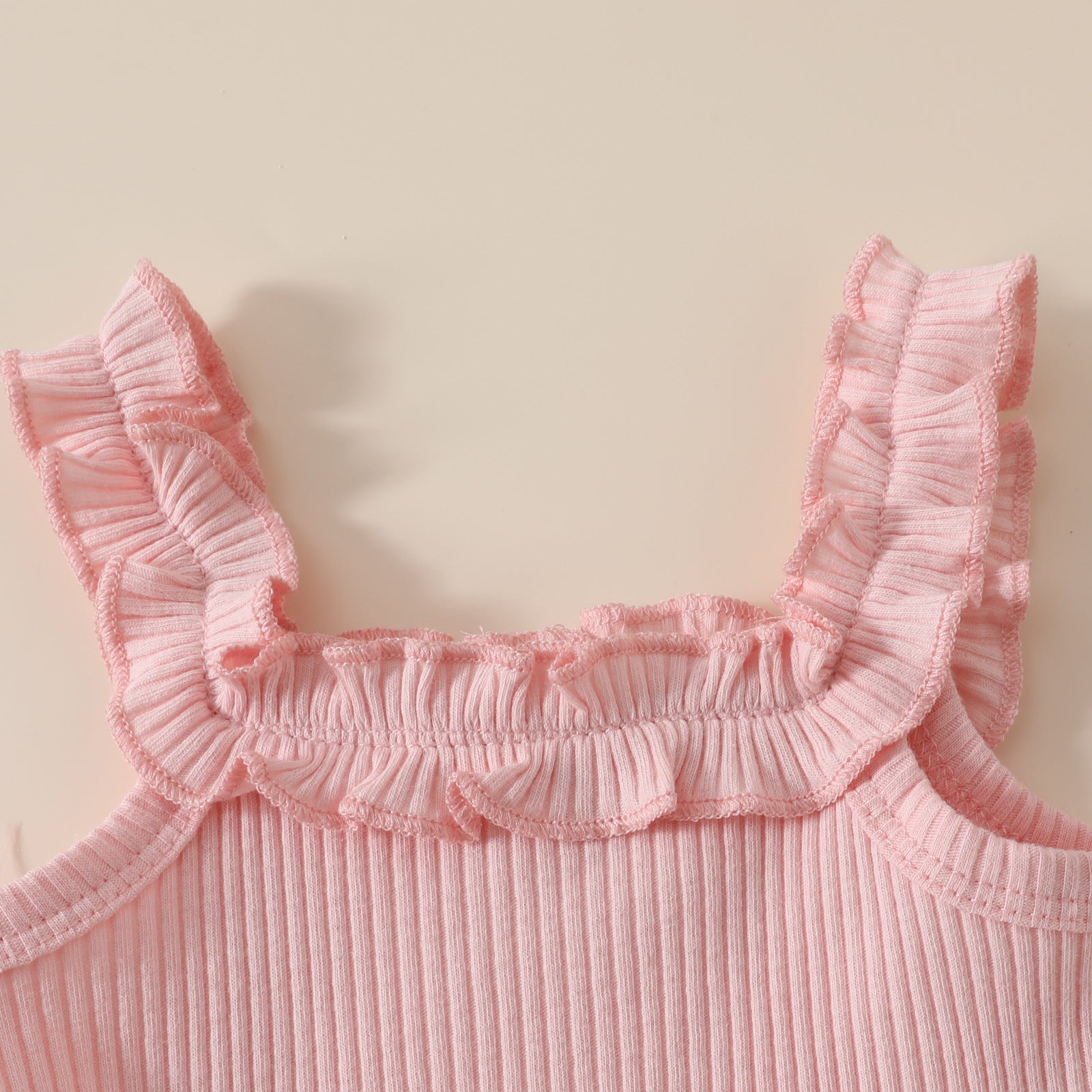 フリル肩ひも付きピンクロンパースの上半身ディテール
