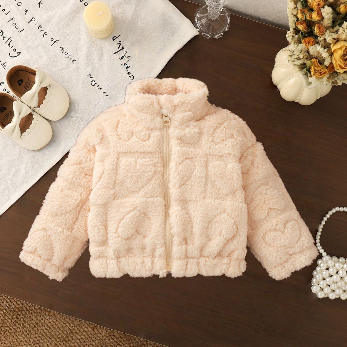 ベージュとピンクの2色展開を見せる子ども用フリースジャケットの並び写真
