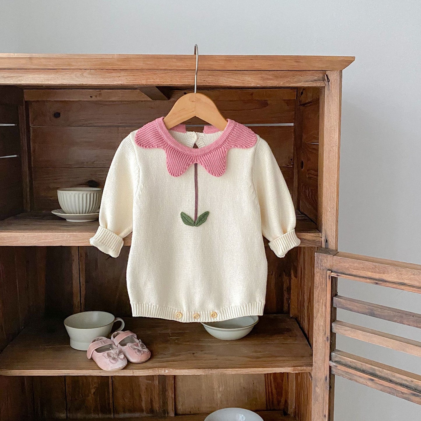 ハンガーにかけられたコットンニットのお花襟長袖ボディスーツ全体写真
