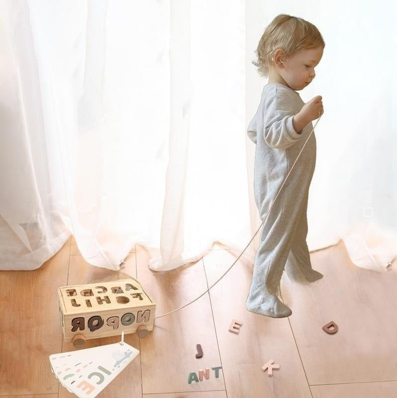 子どもが床で遊ぶ木製アルファベットレターカー 室内の文字あそびシーン
