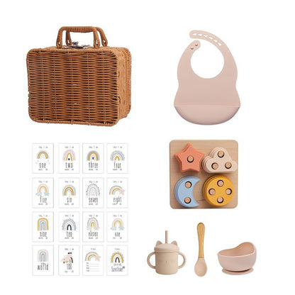 ラタン風バスケットとピンクのシリコンビブ、レインボーカード、星と月モチーフのスタッキングおもちゃ、ピンクのシリコンカップ＆ボウルが並んだセット画像（ベビー用シリコン知育＆テーブルウェアスーツ）
