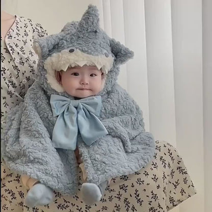 赤ちゃんがサメフード付きのもこもこケープを着用し、正面からデザインが分かるカット
