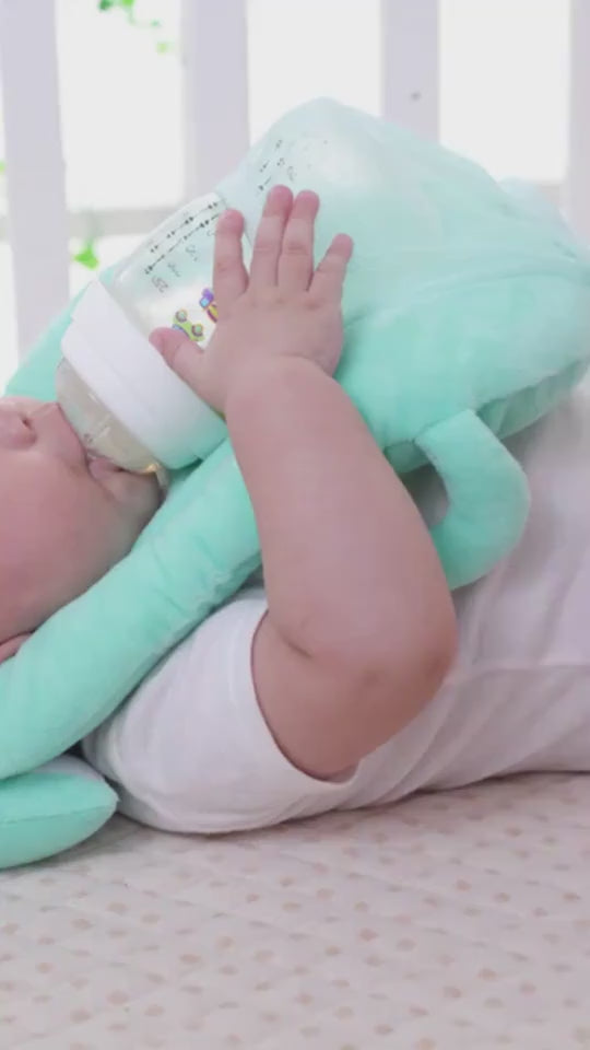 ミントグリーンの授乳クッションに赤ちゃんの頭を乗せて抱き上げているシーンのクローズアップ (ベビー フィーディングピロー 使用例)

