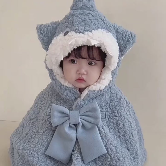 フードをかぶった赤ちゃんのサメケープ着用イメージ（リボンとシルエットが分かる）
