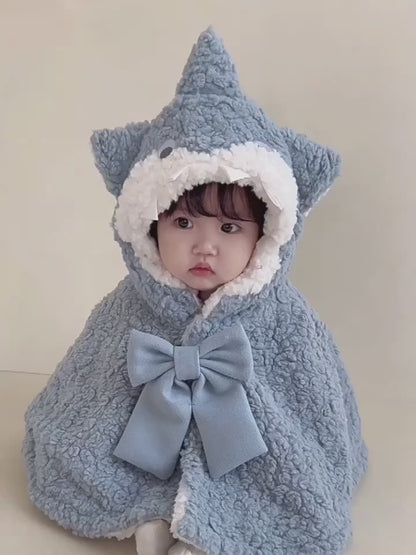 フードをかぶった赤ちゃんのサメケープ着用イメージ（リボンとシルエットが分かる）
