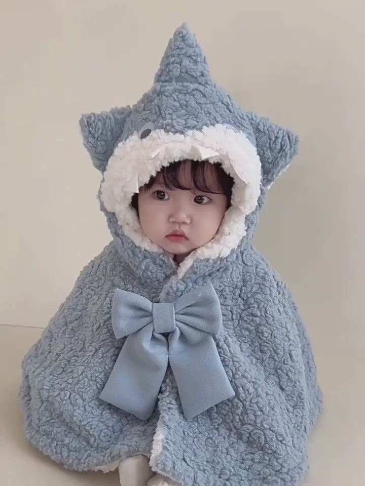 フードをかぶった赤ちゃんのサメケープ着用イメージ（リボンとシルエットが分かる）
