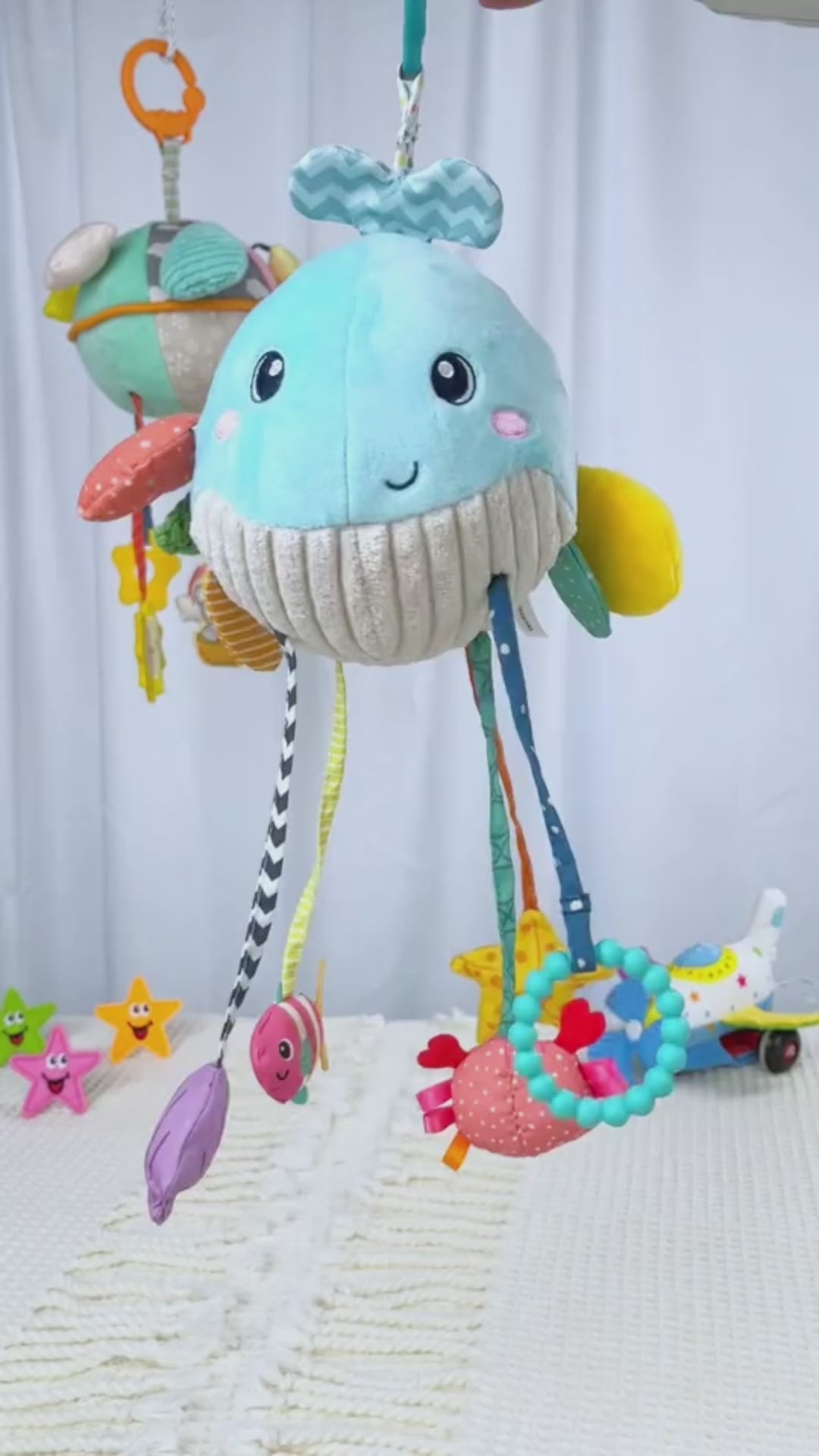 マット上に吊るしたクジラ型ハンギングトイの全体イメージ（ベビーカーおもちゃ）
