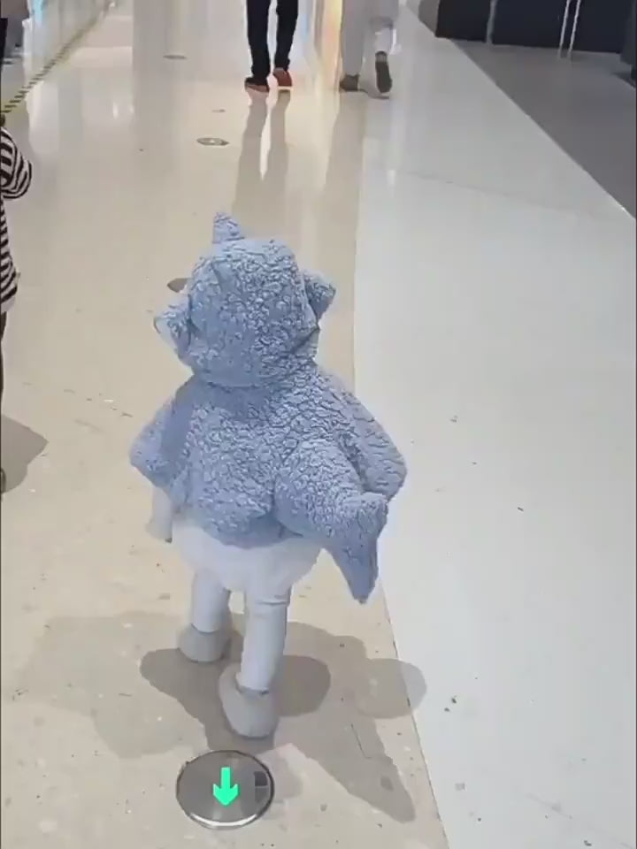 室内で子どもがサメフード付きケープを着て歩く様子が分かる後ろ姿
