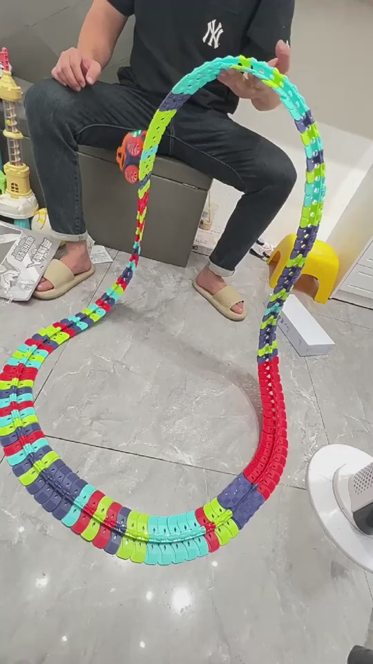 大人の手がフレキシブルレールパーツをつなぎ合わせてコースを組み立てている動画サムネイル
